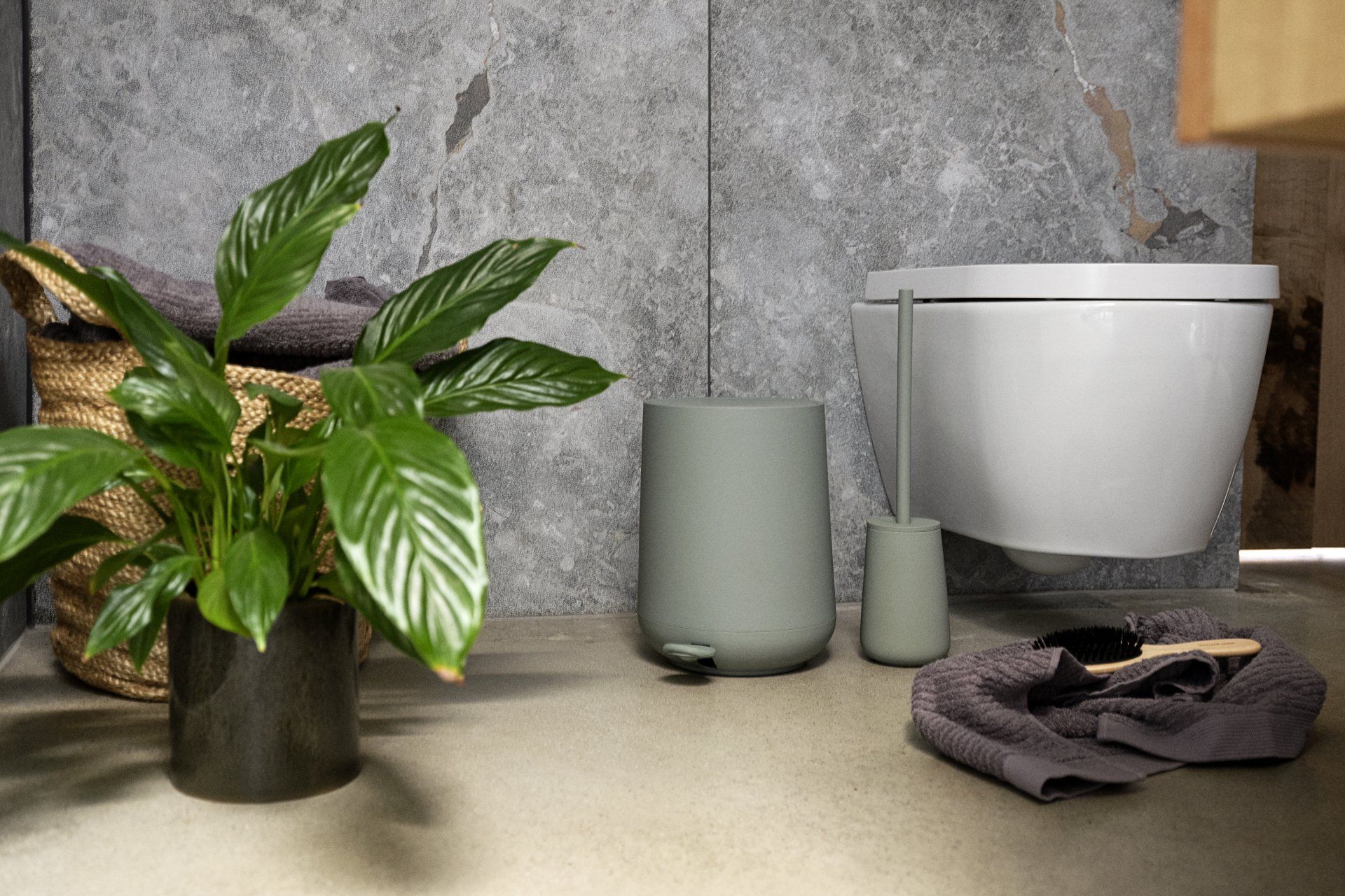 Ein Badezimmer mit Toilette, Mülleimer, Handtüchern und einer Pflanze.