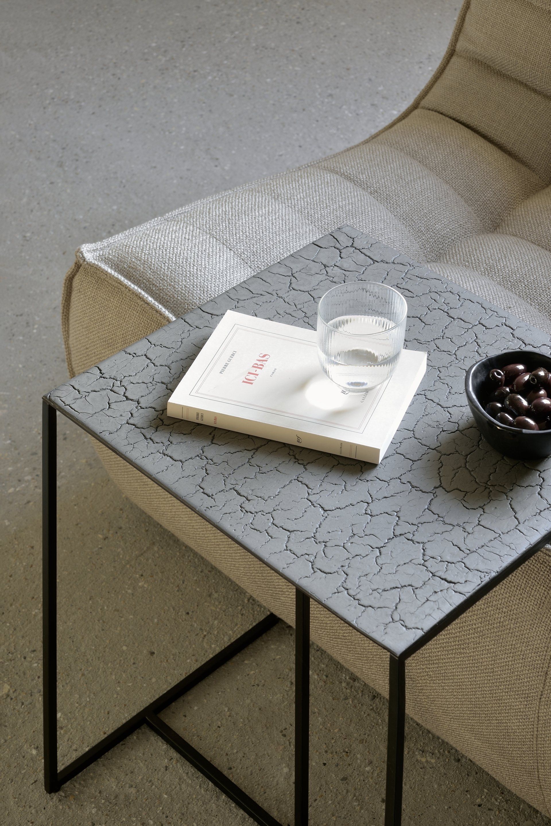 Ein Buch und ein Glas Wasser liegen auf einem Tisch neben einem Stuhl.