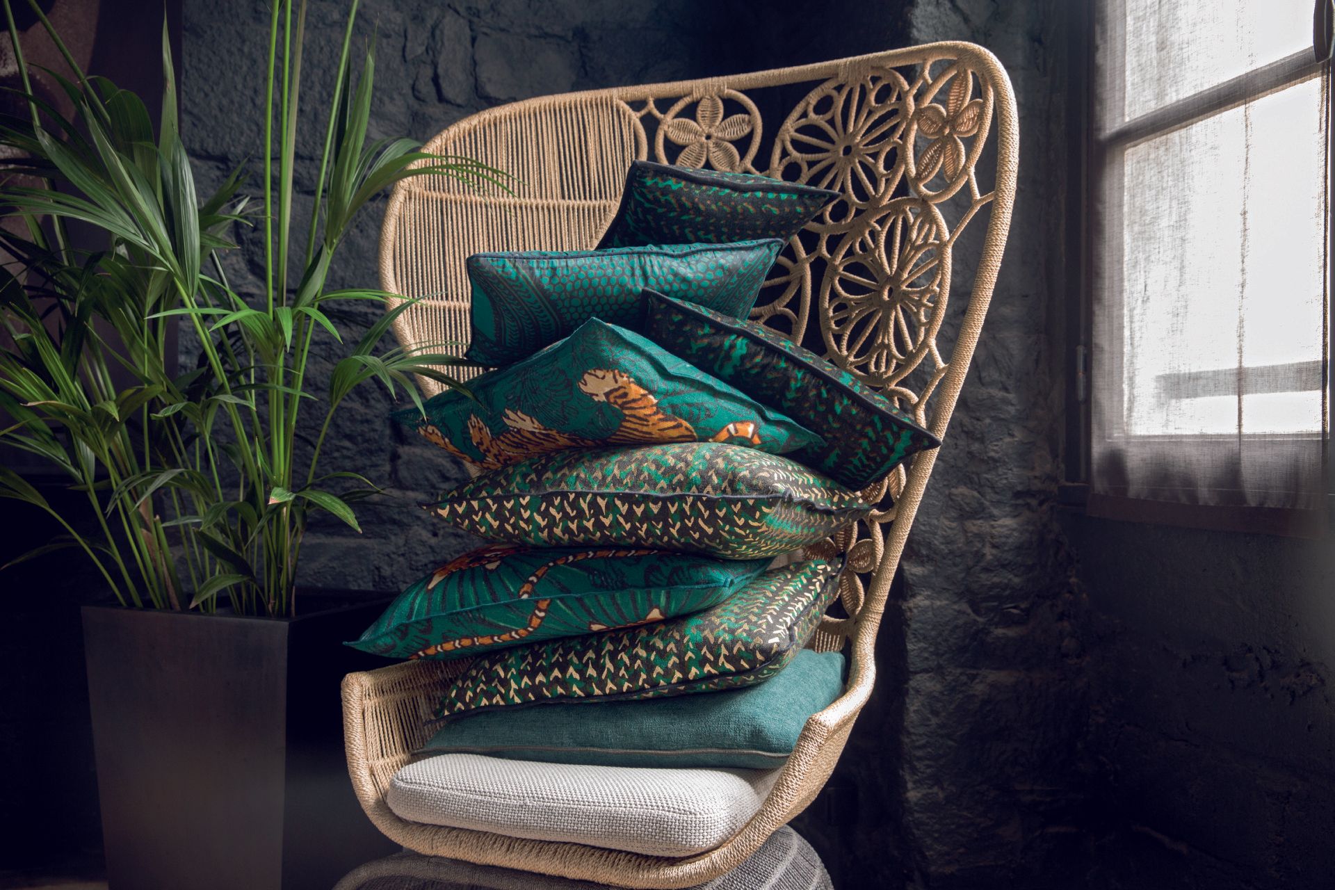 Ein Korbstuhl mit gestapelten grünen Kissen darauf.