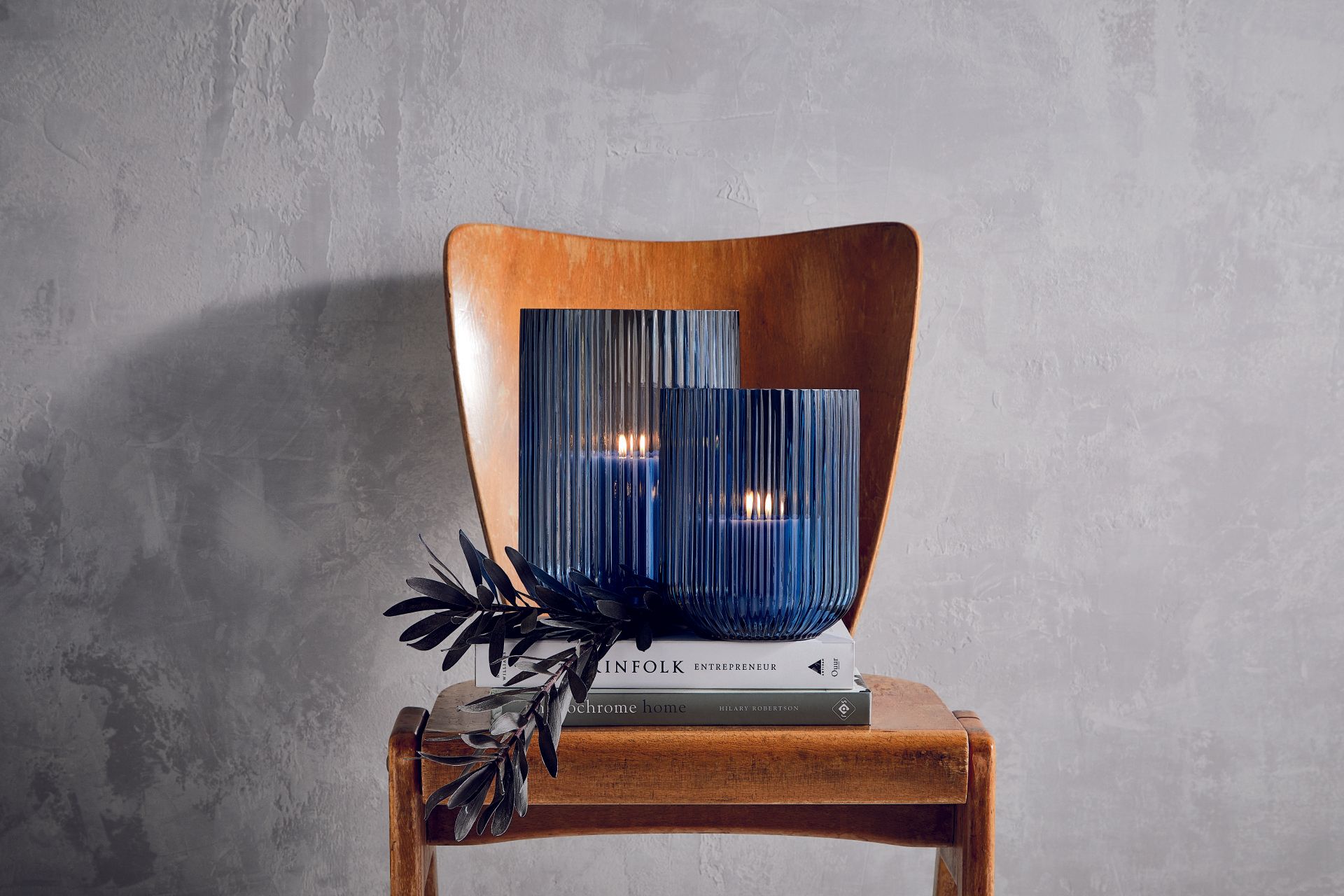 Ein Holzstuhl mit zwei Kerzen darin und einem Buch darauf.