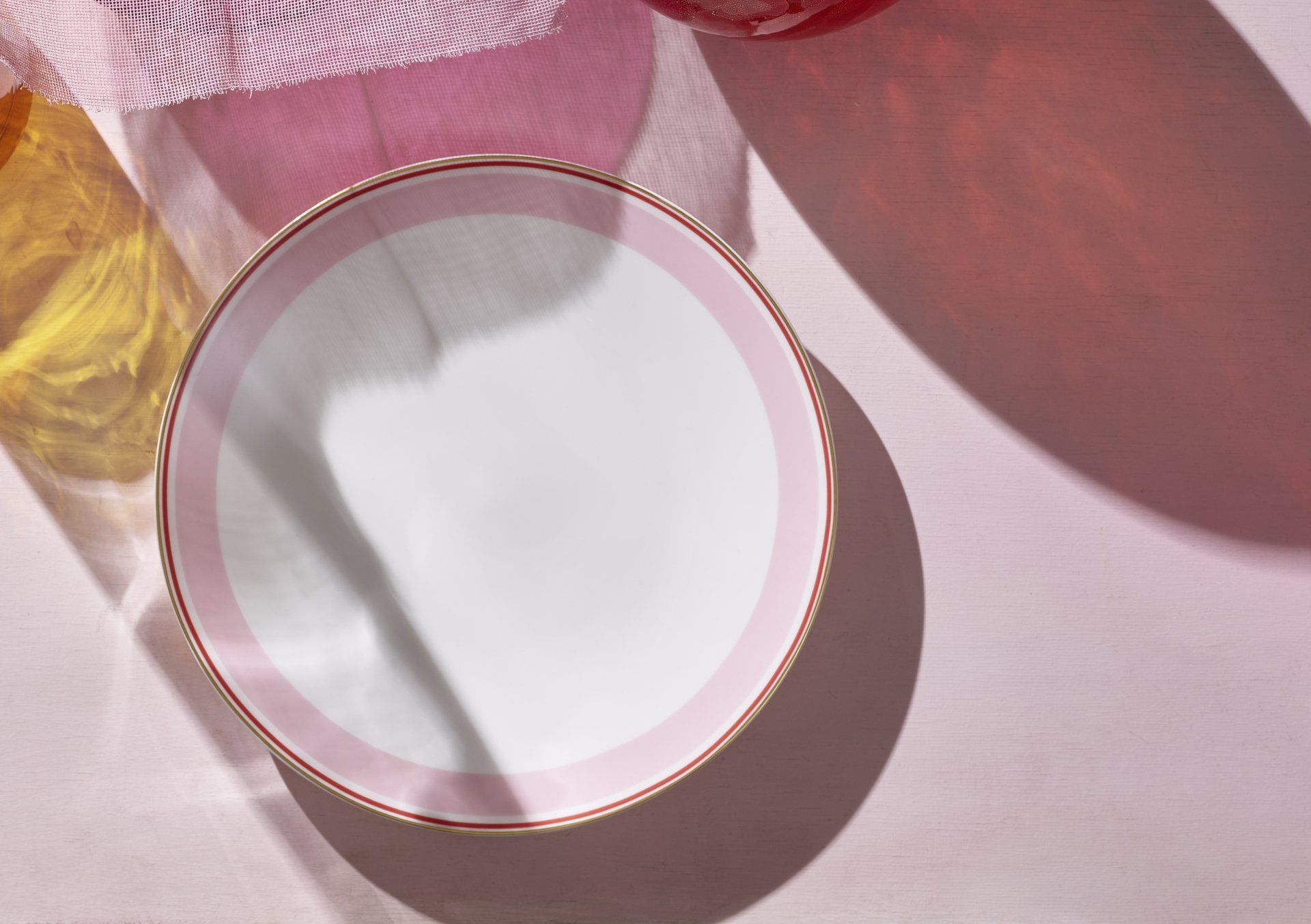 Auf einem rosa Tisch steht ein weißer Teller mit rosa Rand.