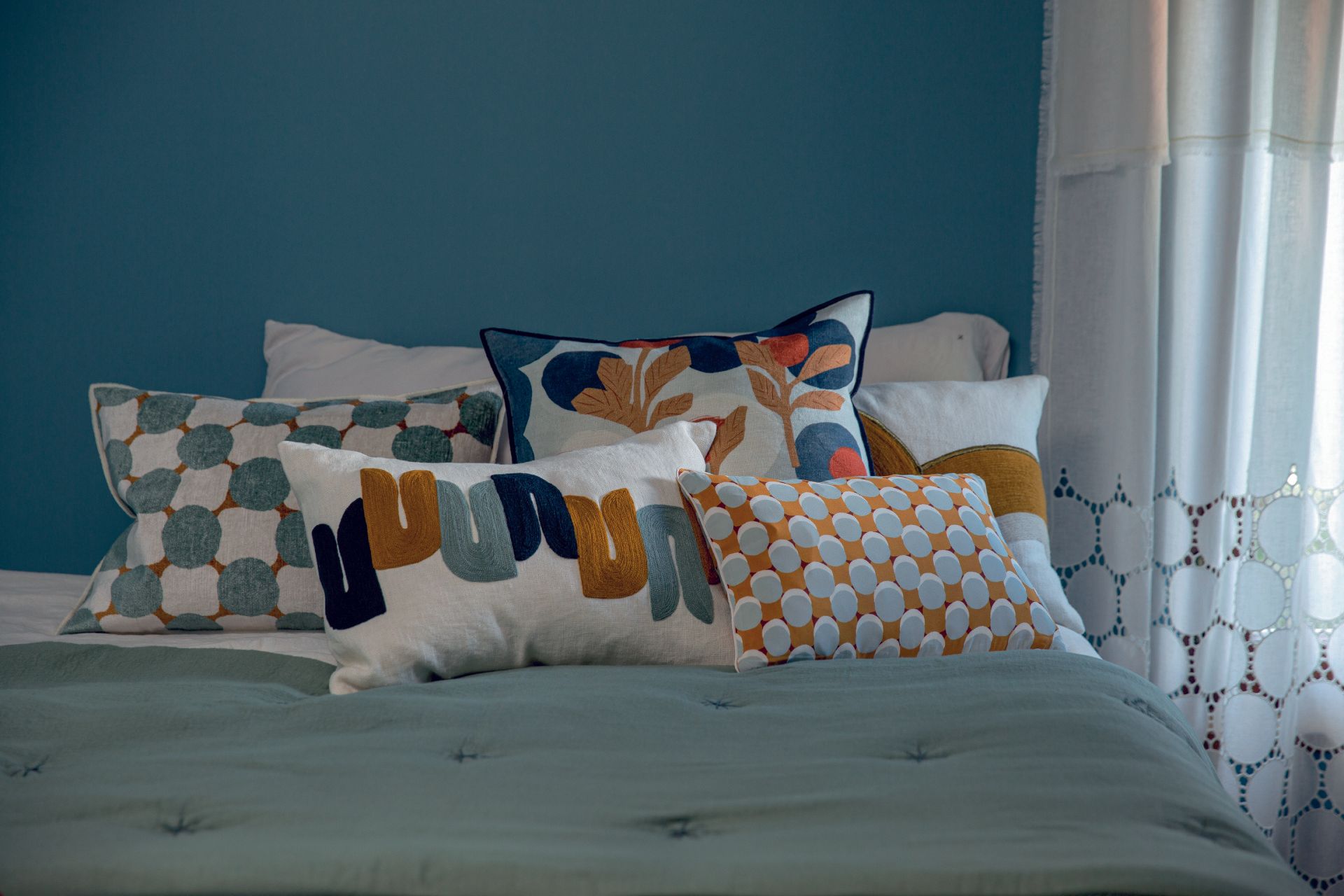 Ein Bett mit vielen Kissen darauf und einer blauen Wand.