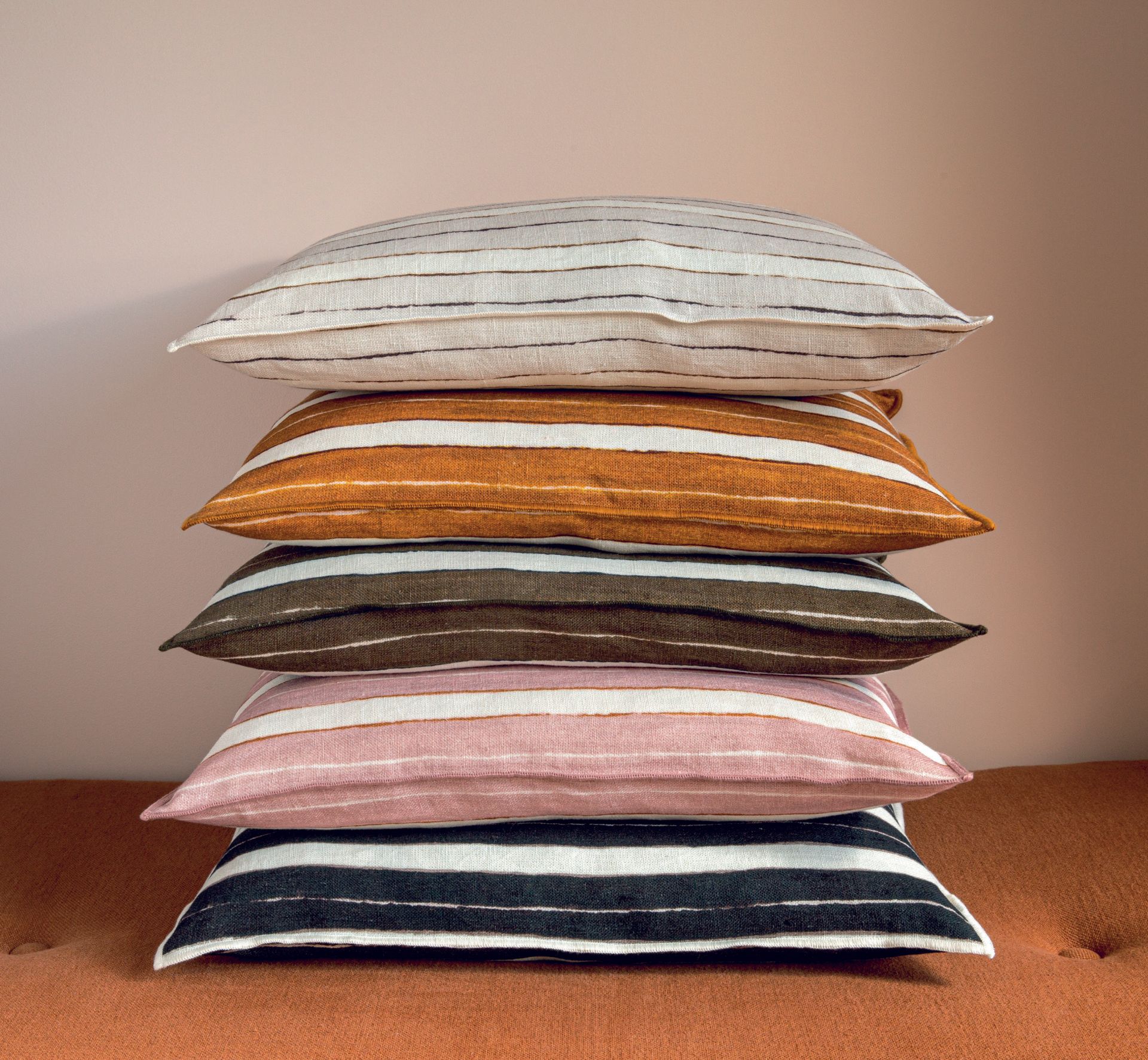 Ein Stapel gestreifter Kissen, die übereinander auf einem Sofa liegen.