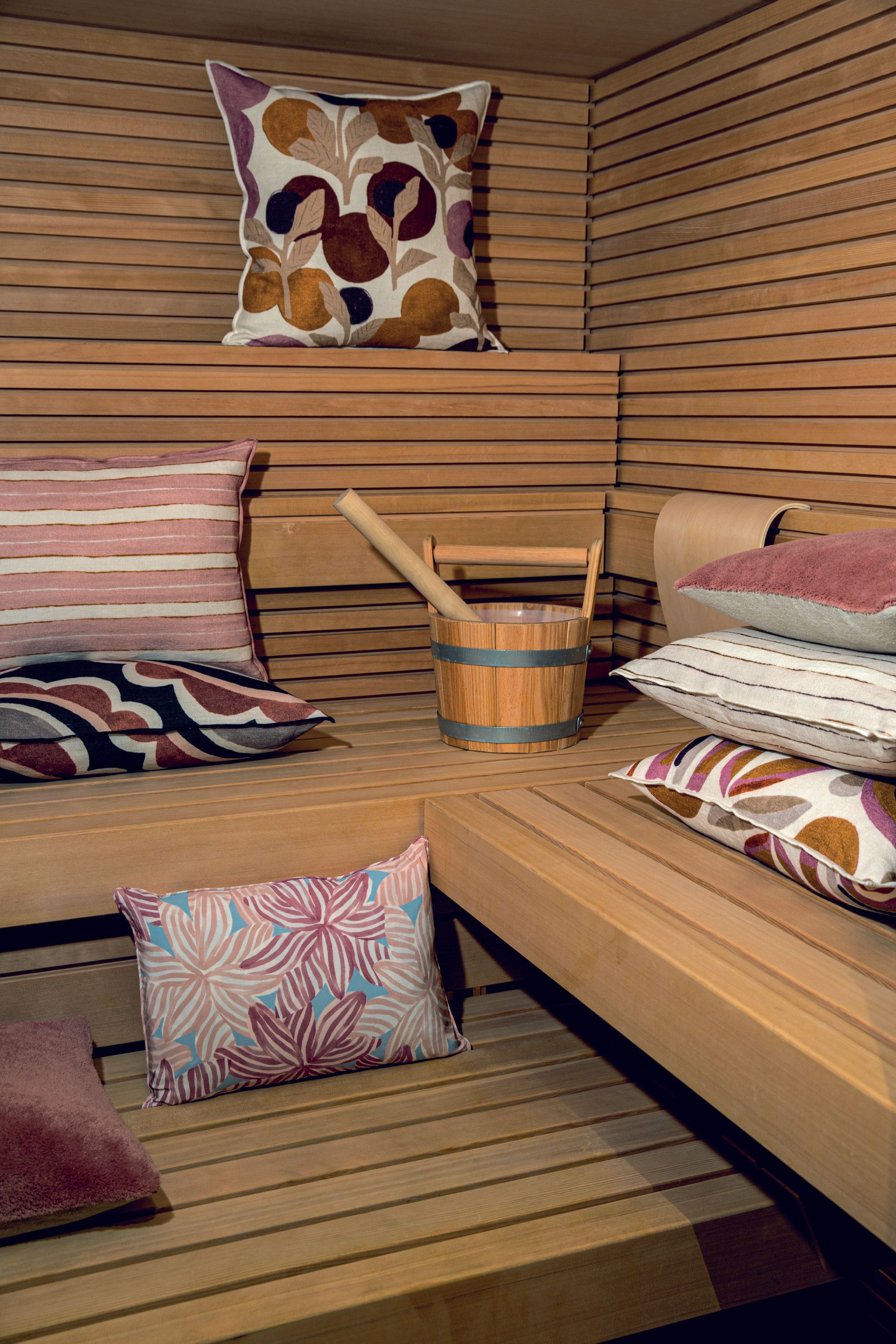 Eine Holzsauna mit vielen Kissen und einem Holzeimer.