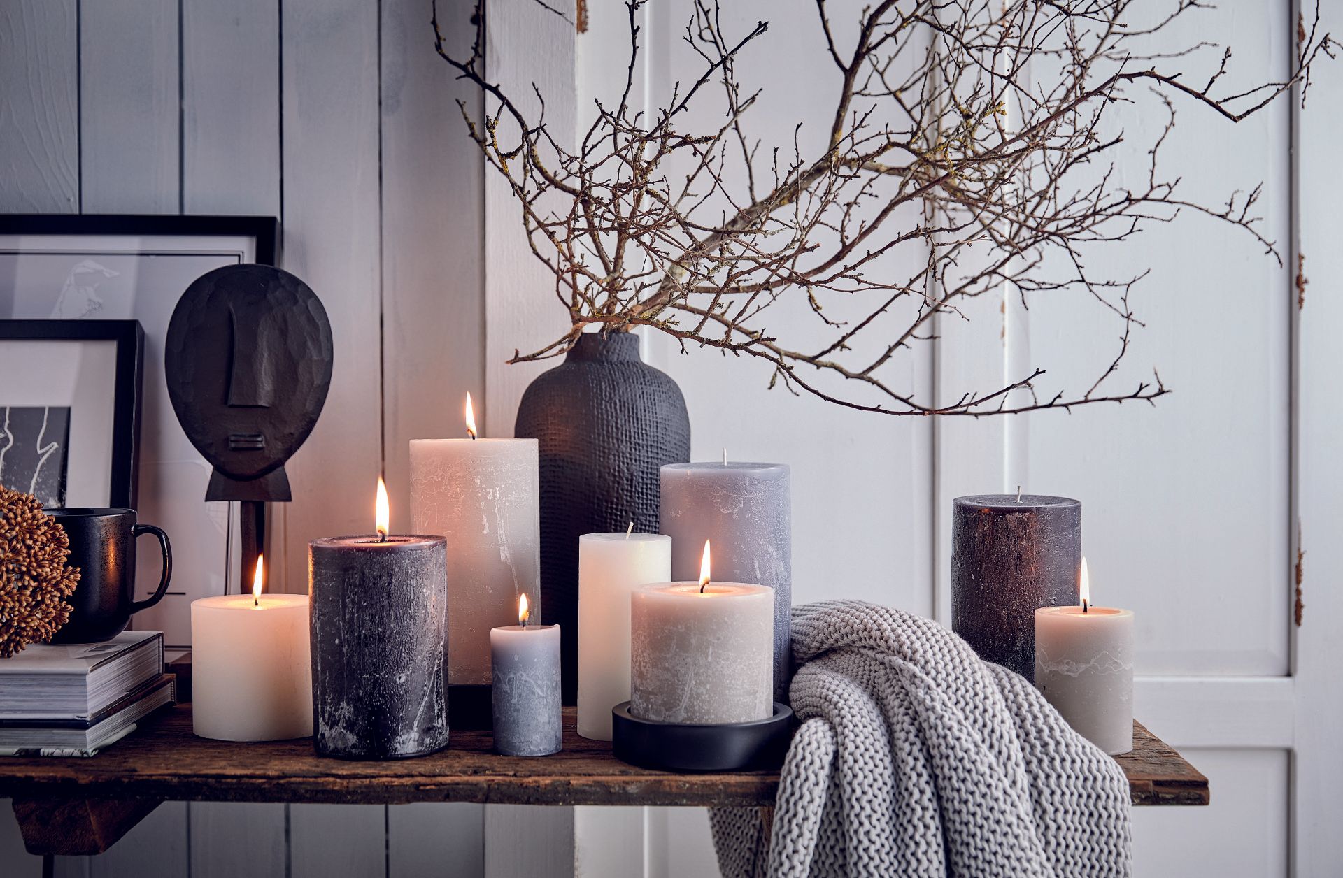 Ein Regal voller Kerzen und eine Vase mit Zweigen.