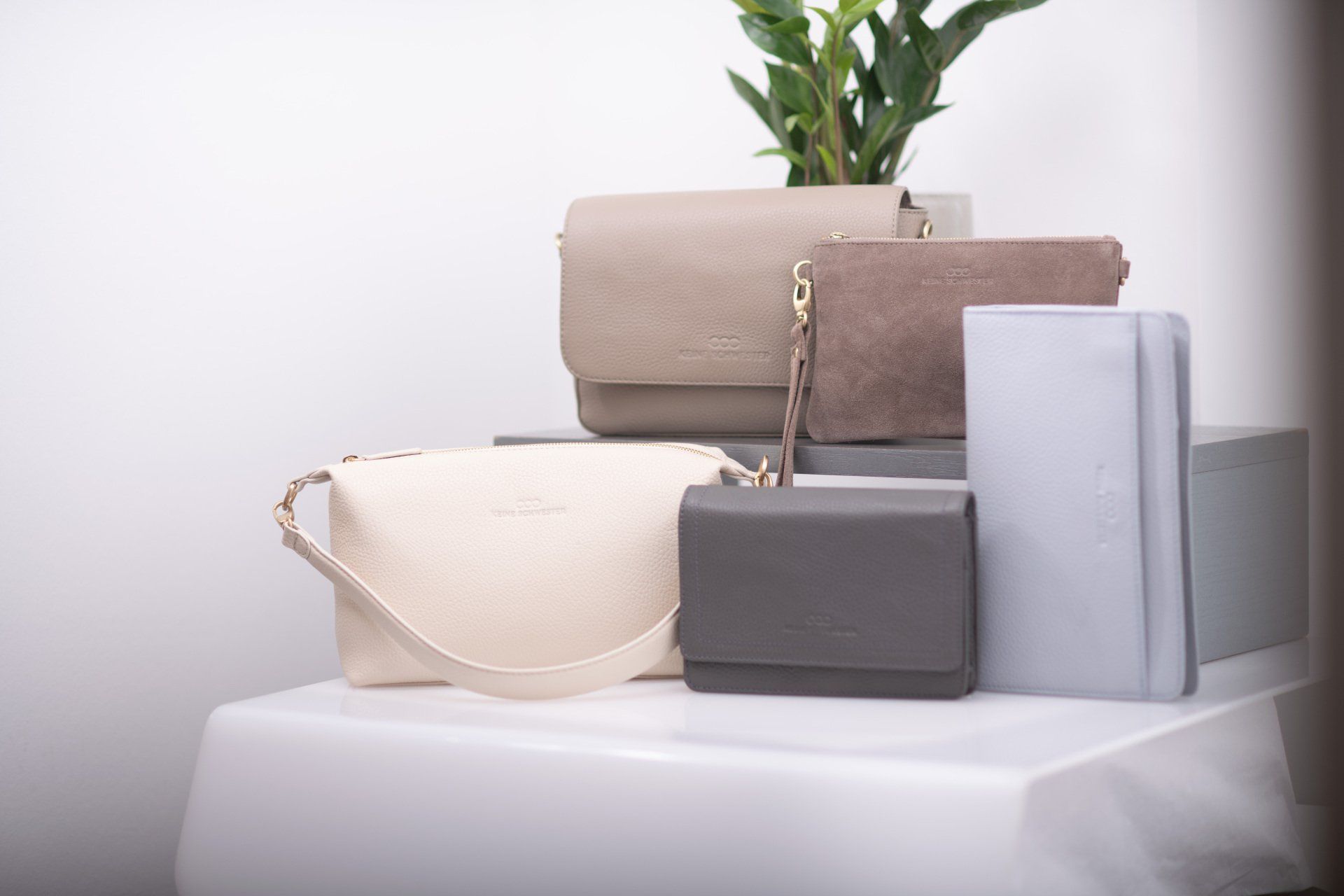 Auf einem Tisch liegen mehrere Handtaschen und Geldbörsen übereinander gestapelt.