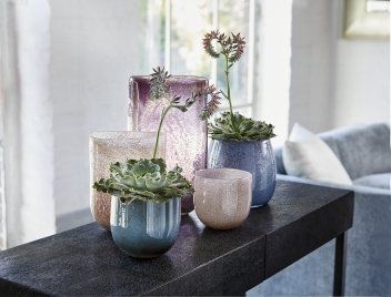 Auf einem Tisch steht eine Gruppe mit Blumen gefüllter Vasen.