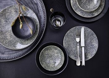 Ein Tisch mit Tellern, Schüsseln, Besteck und einem Glas.