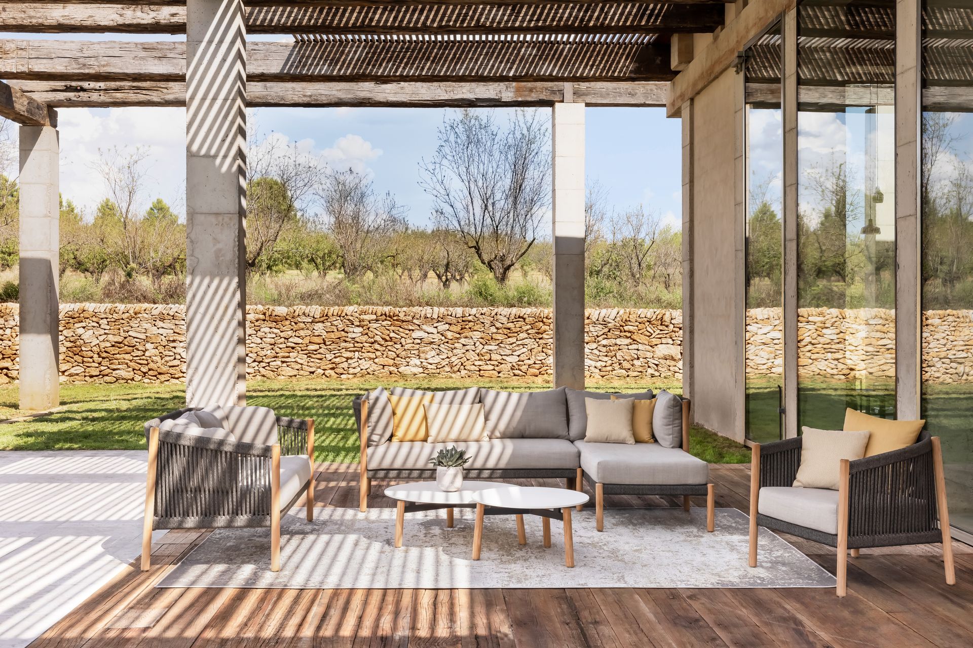 Eine Terrasse mit Sofa, Stühlen, Tisch und Teppich.