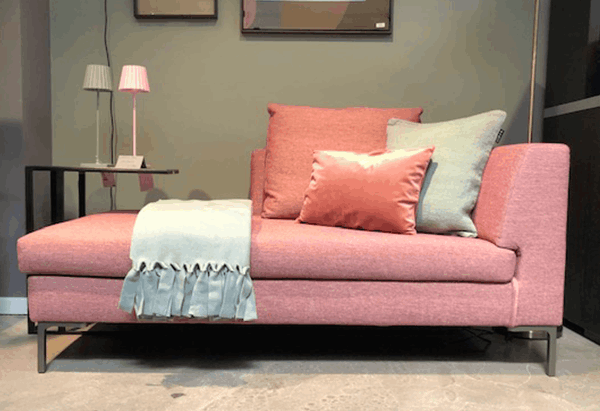 Eine rosa Chaiselongue mit Kissen und einer Decke darauf