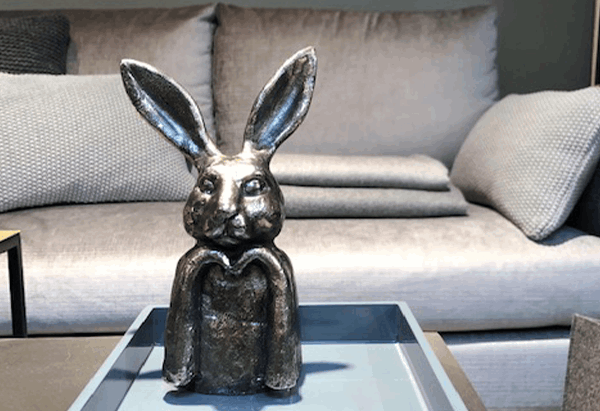 Eine Statue eines Kaninchens sitzt auf einem Tisch vor einem Sofa
