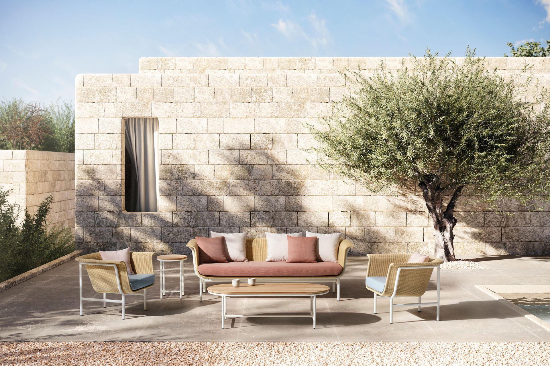 Eine Terrasse mit Sofa, Stühlen, Tischen und einem Baum vor einem Steingebäude.