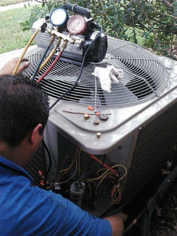 a man in a blue shirt is working on an air conditioner .