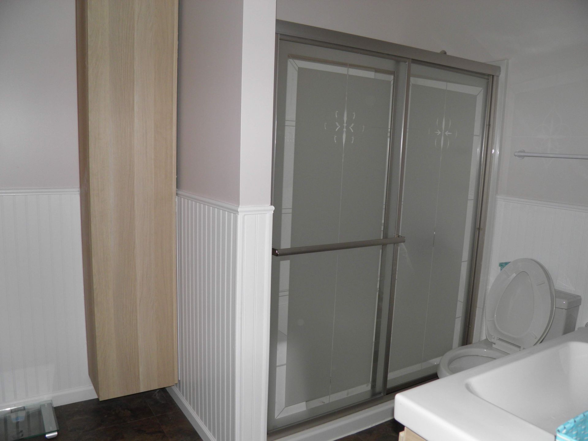 Bathroom with a tub, toilet, and vanity. Gray tile, turquoise towels, and a decorative wall hanging.