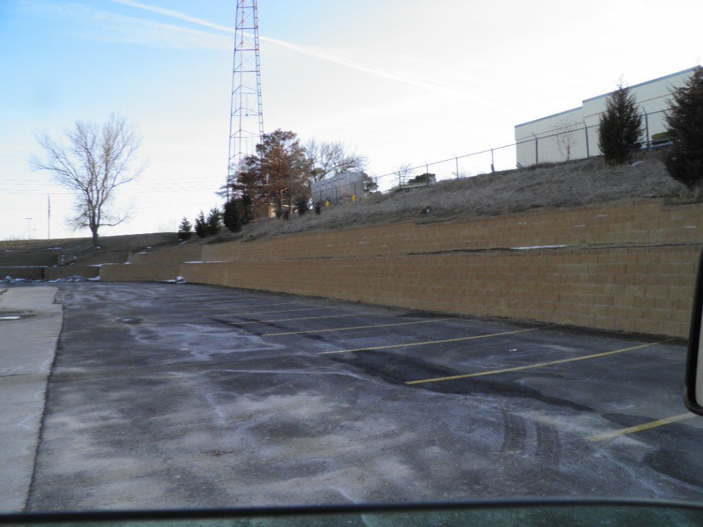 Parking lot with retaining wall and bare trees under a clear sky; a tower is in the background. Parking lot with retaining wall and bare trees under a clear sky; a tower is in the background.