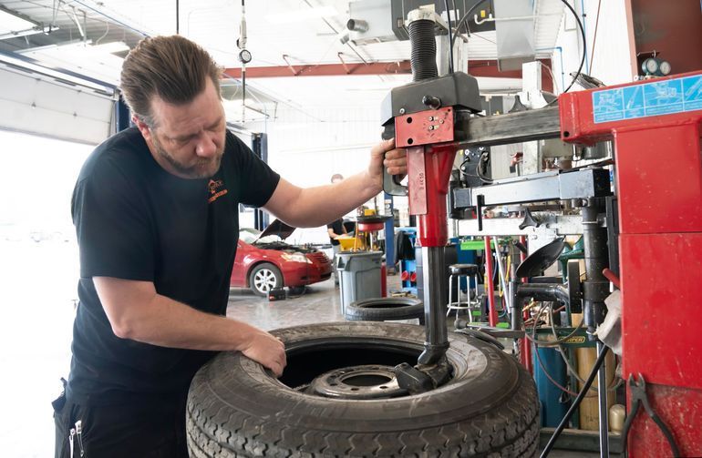 Mechanic using a tire-changing machine in an auto repair shop