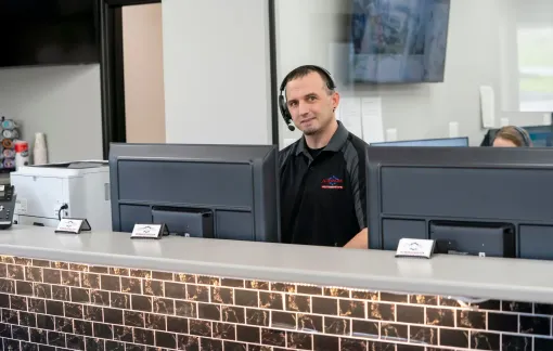 Man standing behind a front desk with computer monitors in a modern lobby