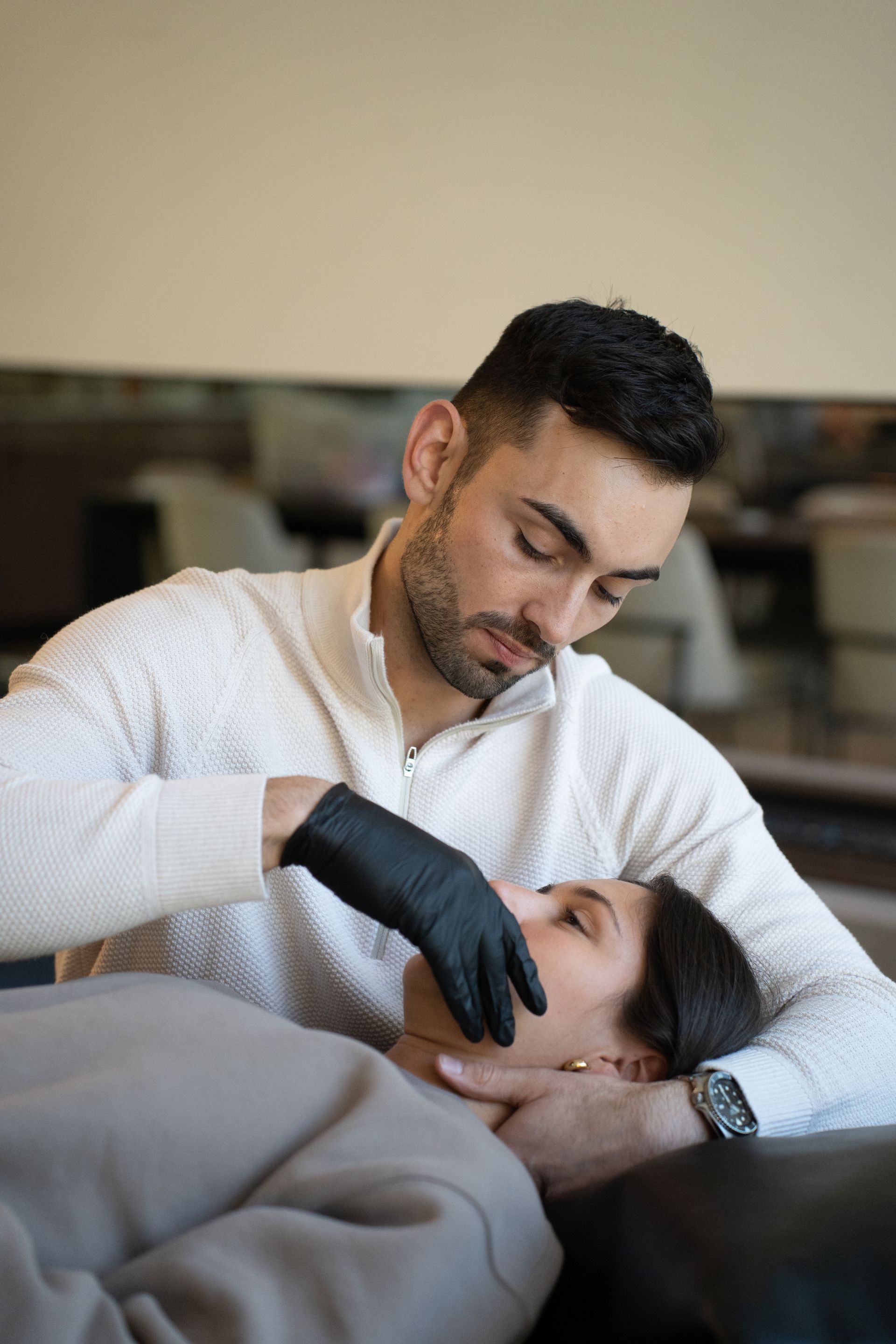 Dentist examining a patient’s mouth during a checkup, wearing black gloves and a white shirt.