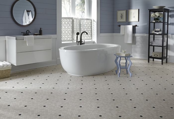 Bathroom with a freestanding white tub, blue walls, a sink, and patterned floor.