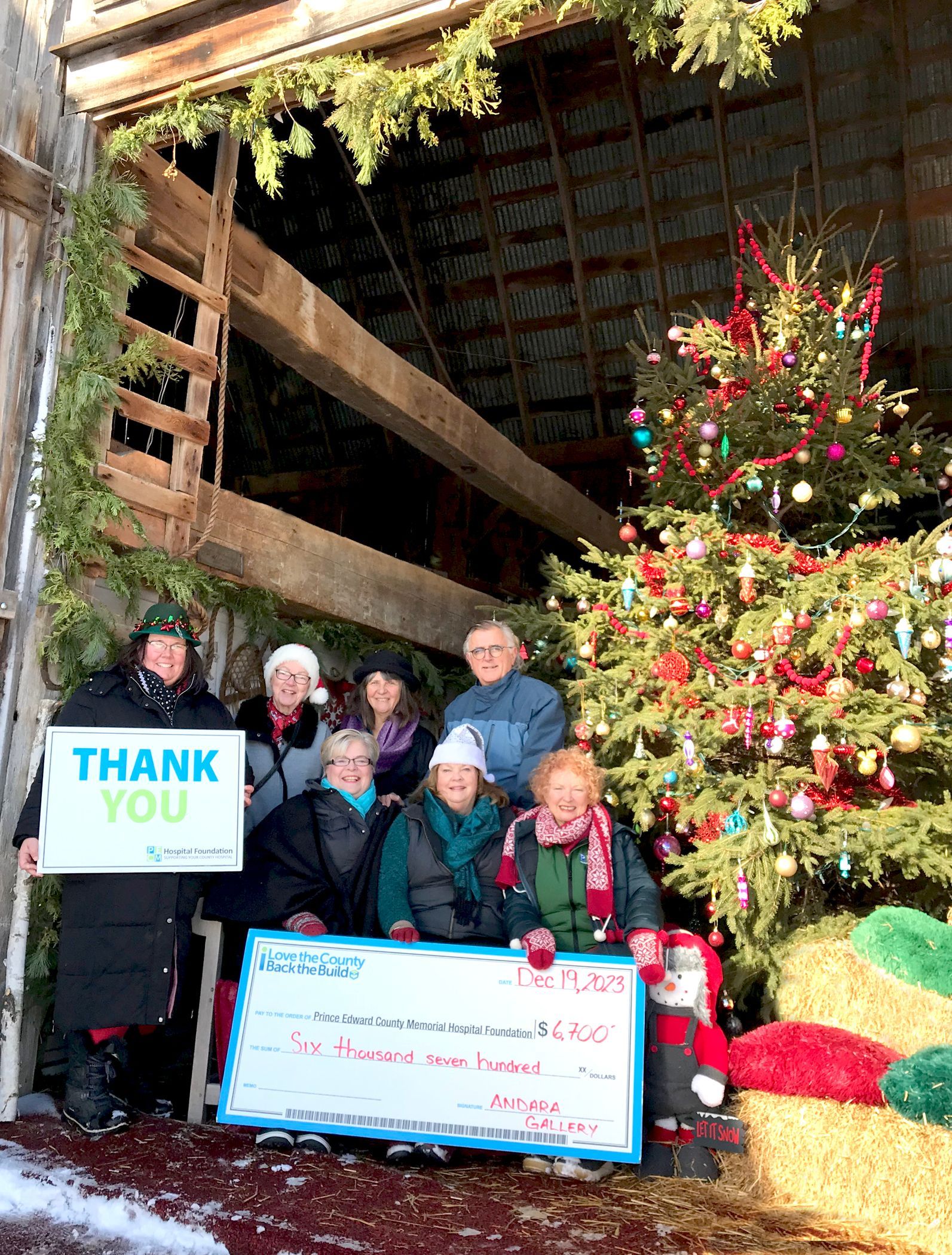 Cheque presentation photo in front of the Christmas tree at ANDARA Gallery.