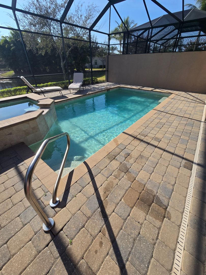 Small outdoor pool with brick patio, surrounded by a screen enclosure and a spa.