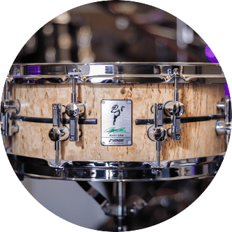 A close-up of a wooden Sonor snare drum with chrome hardware in a music store.