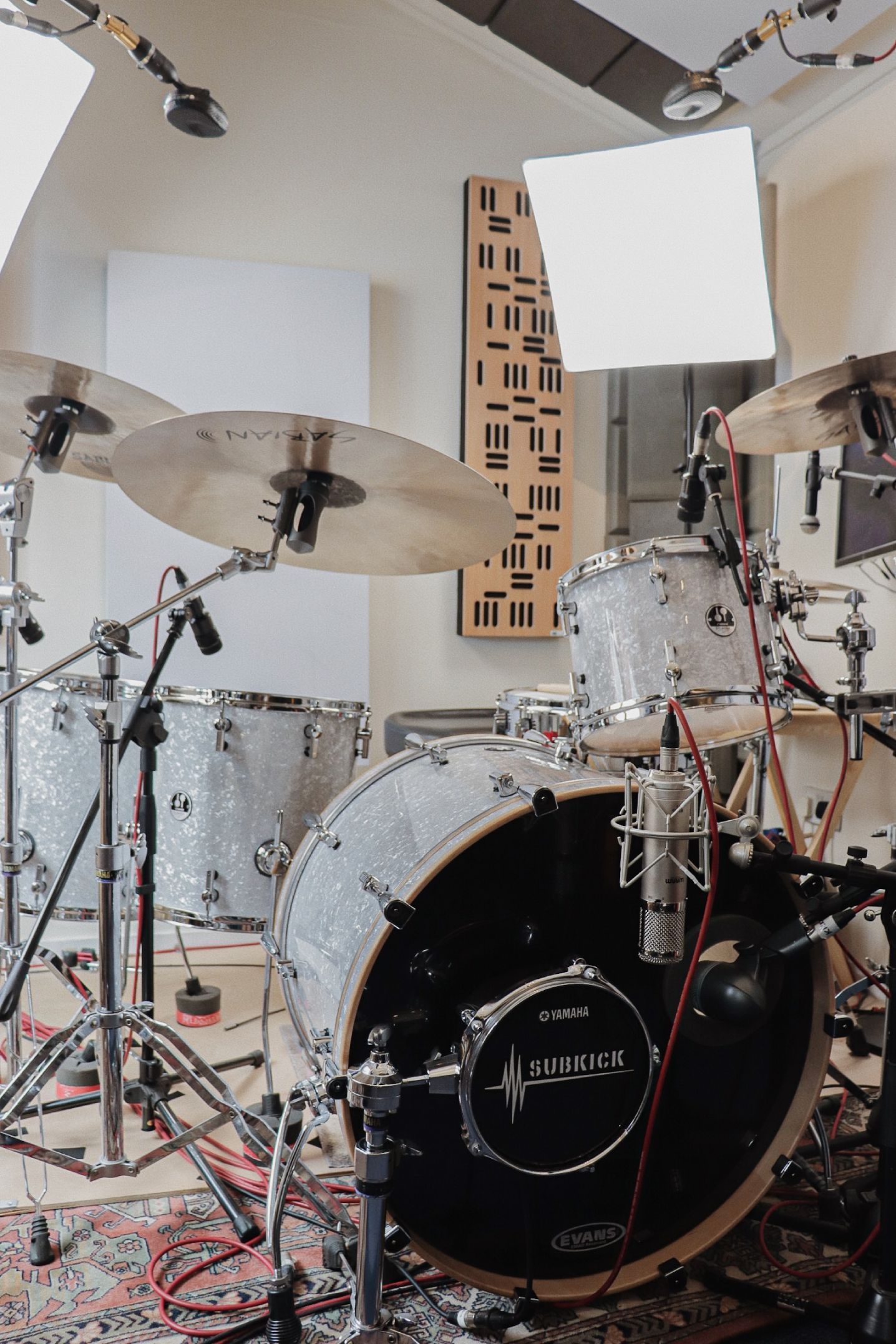 Drum set in a recording studio, with microphones. Drums are white sparkly.