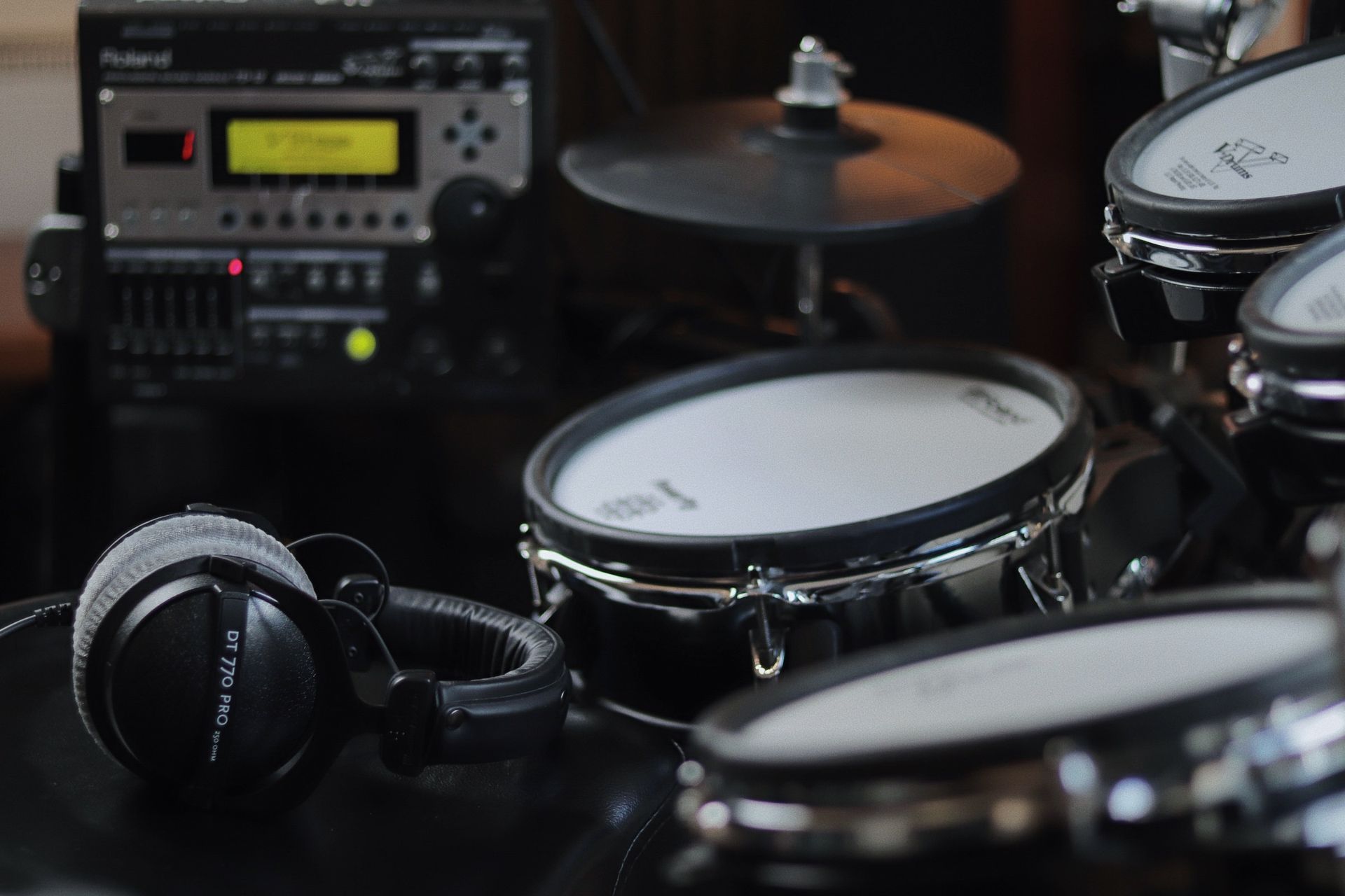 Two black microphones on stands, blurred background of a drum set and stage lights.