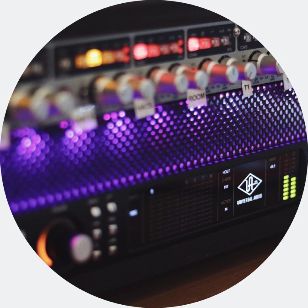 Rack-mounted audio equipment, glowing purple lights, Universal Audio interface, knobs and displays.