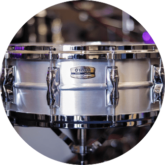 Silver Yamaha snare drum with chrome hardware on a stand.
