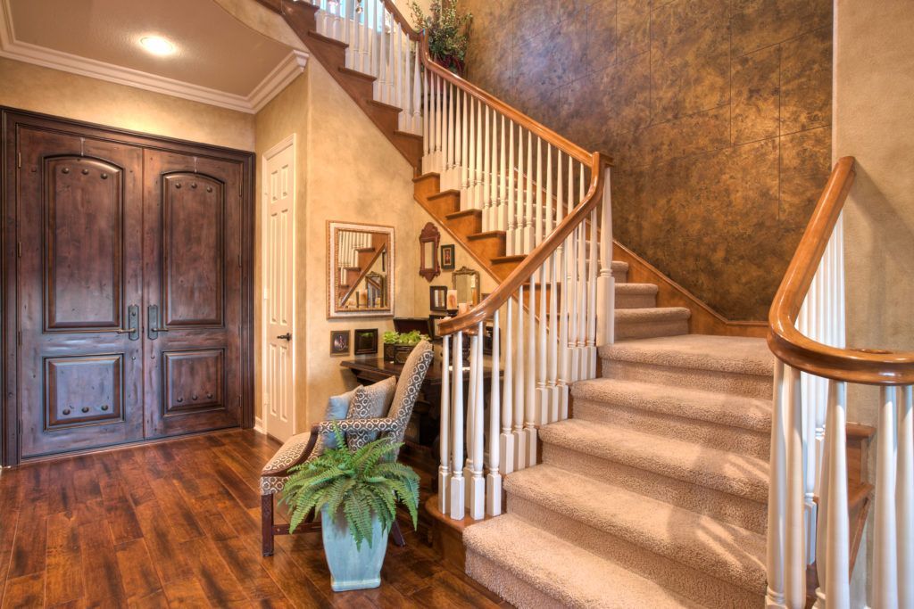 A staircase in a house with a wooden railing and carpeted steps.