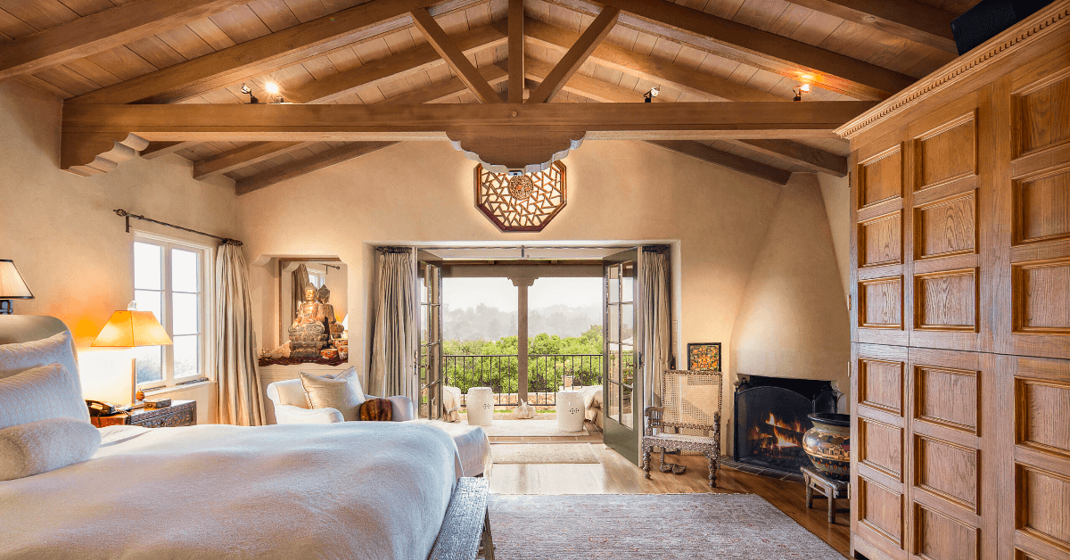 A bedroom with a large bed , fireplace , and lots of windows.