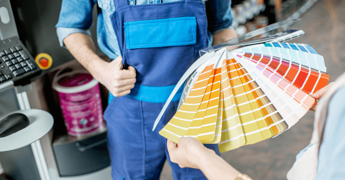 A man is holding a palette of paint while a woman holds a palette of paint.