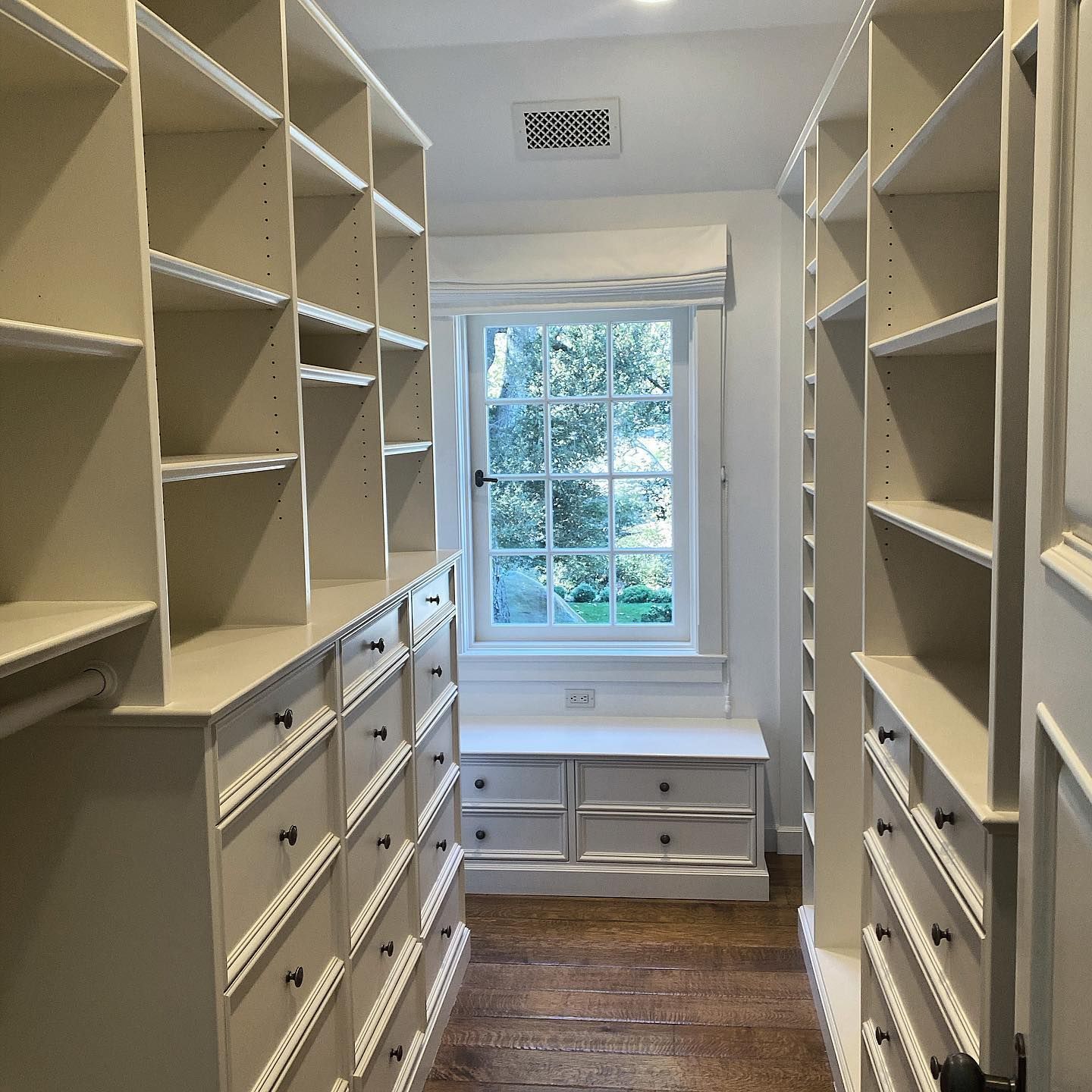 A walk in closet with lots of shelves and drawers