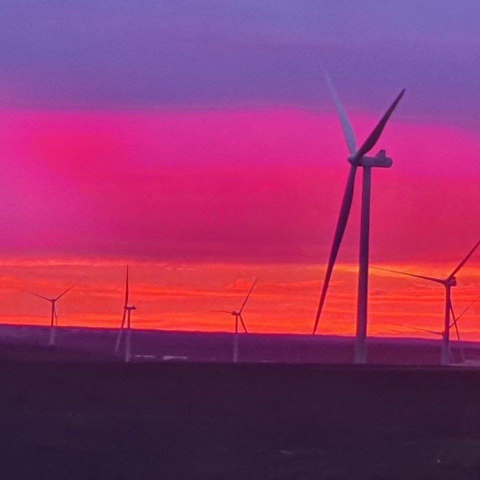 A group of wind turbines against a sunset sky