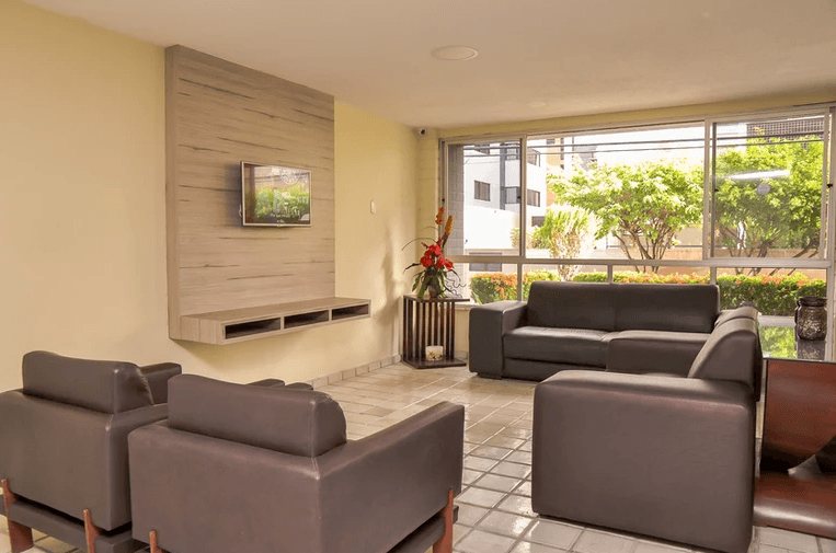 Uma sala de estar com um sofá, cadeiras e uma TV de tela plana.