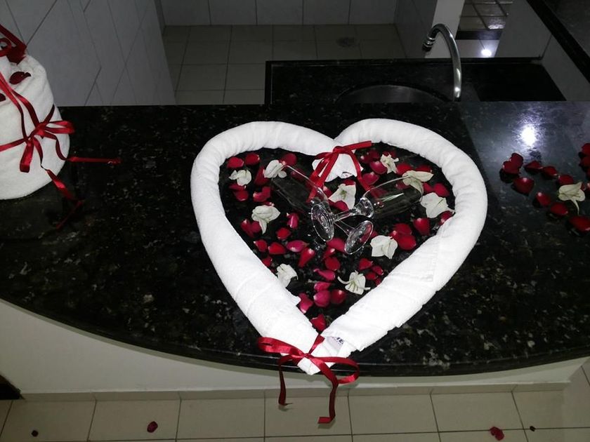 Uma toalha em forma de coração está sobre um balcão com pétalas de rosa