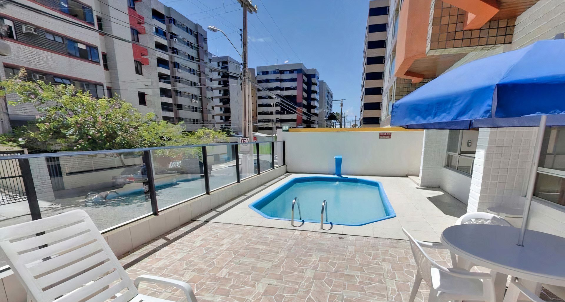 Há uma piscina no quintal de um prédio.