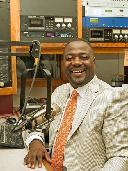 A man in a suit and tie is sitting in front of a microphone.