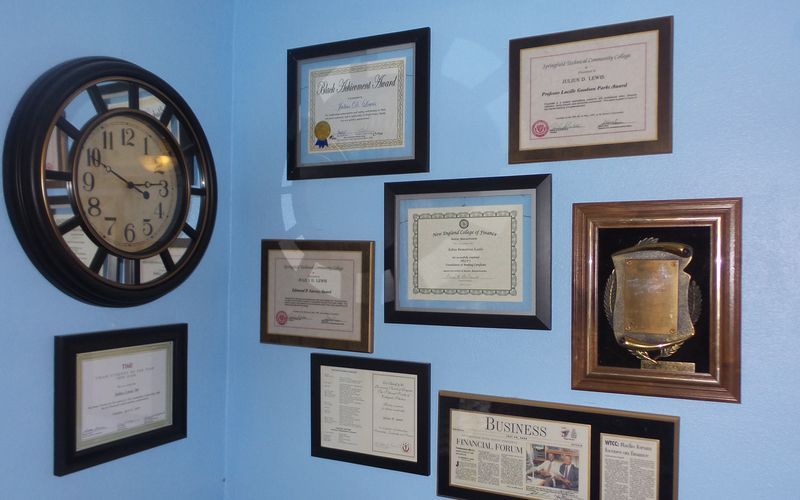 A clock hanging on a wall next to a bunch of framed pictures