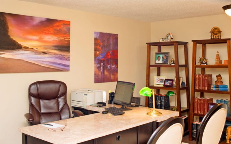 A home office with a desk and chairs and a painting on the wall
