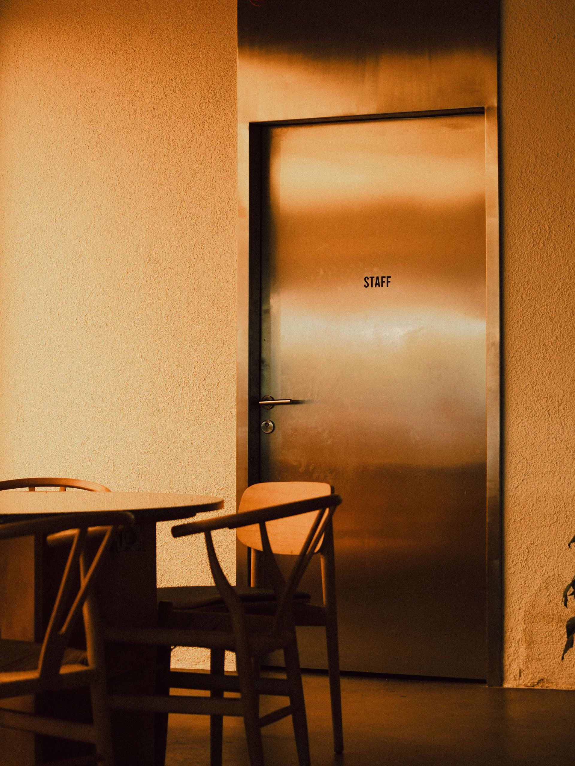 Dim room with a closed door and two chairs beside a small table.