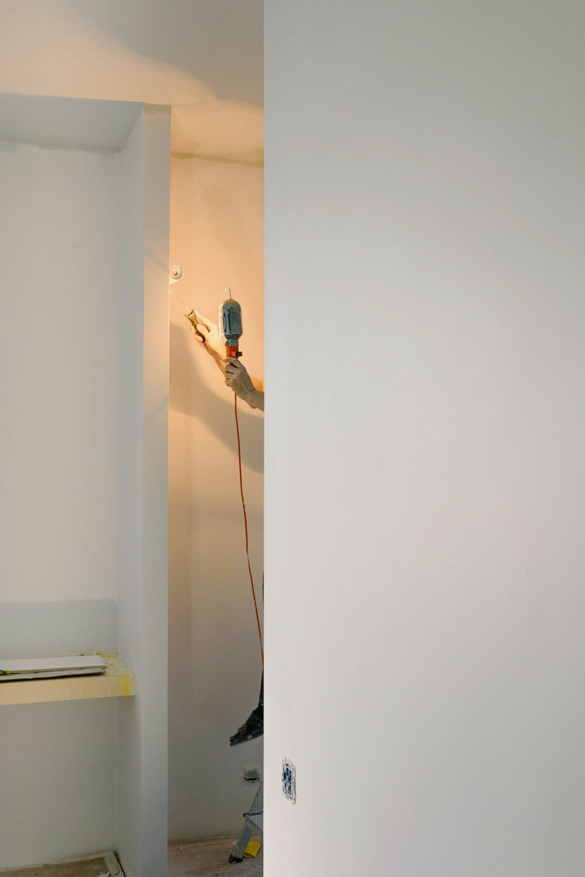 Partially open closet door revealing a white room and a hanging tool on the wall