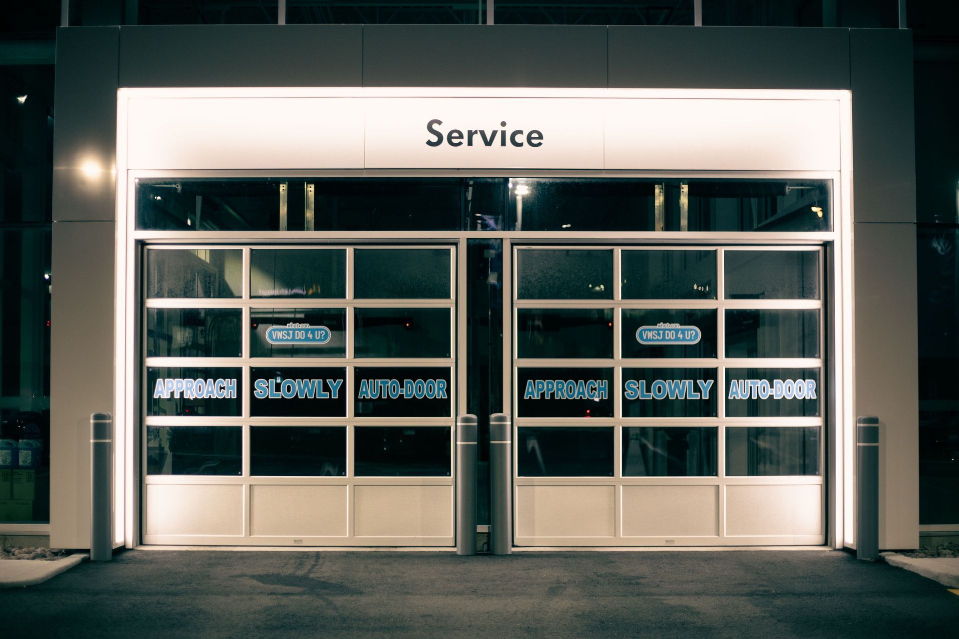 Modern glass garage with illuminated “Service” sign at night