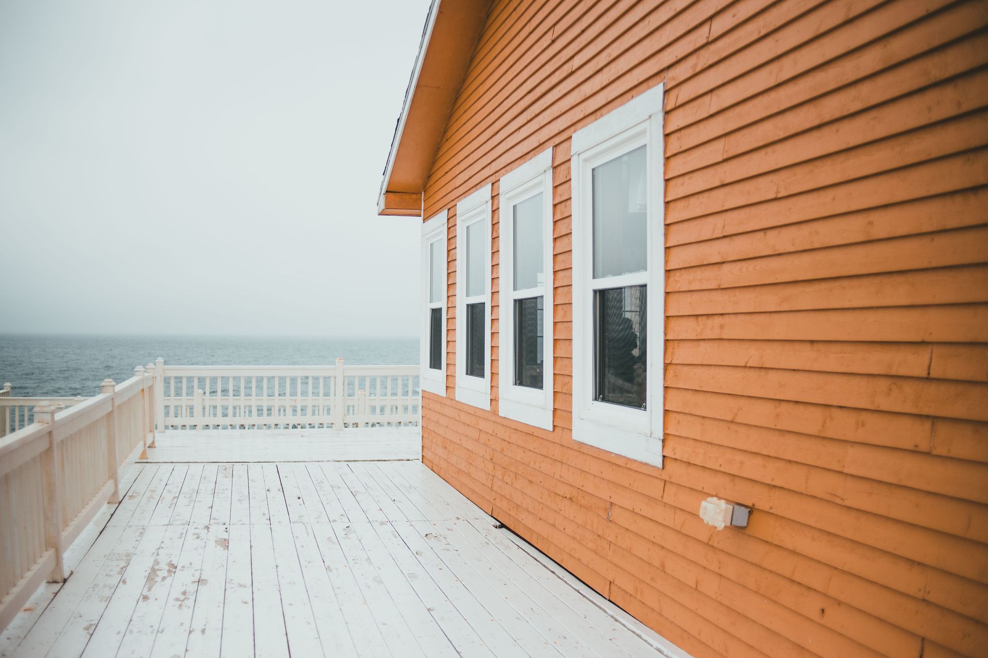 Orange beach house with white trim and deck overlooking the ocean