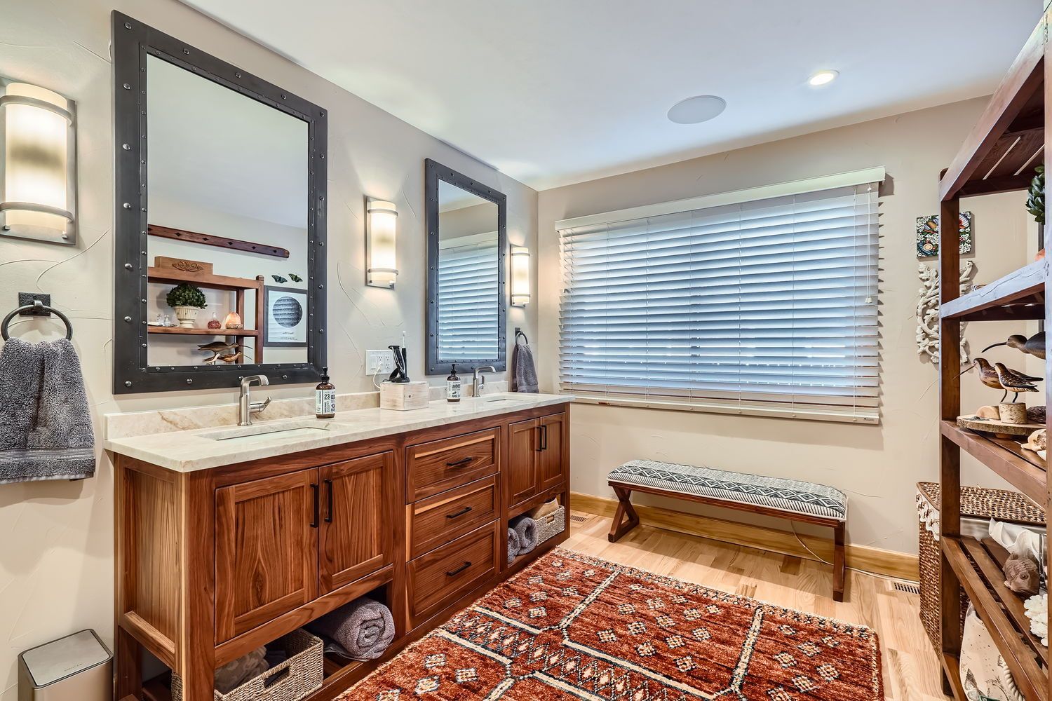 Bathroom with double vanity, two mirrors, and a patterned rug.
