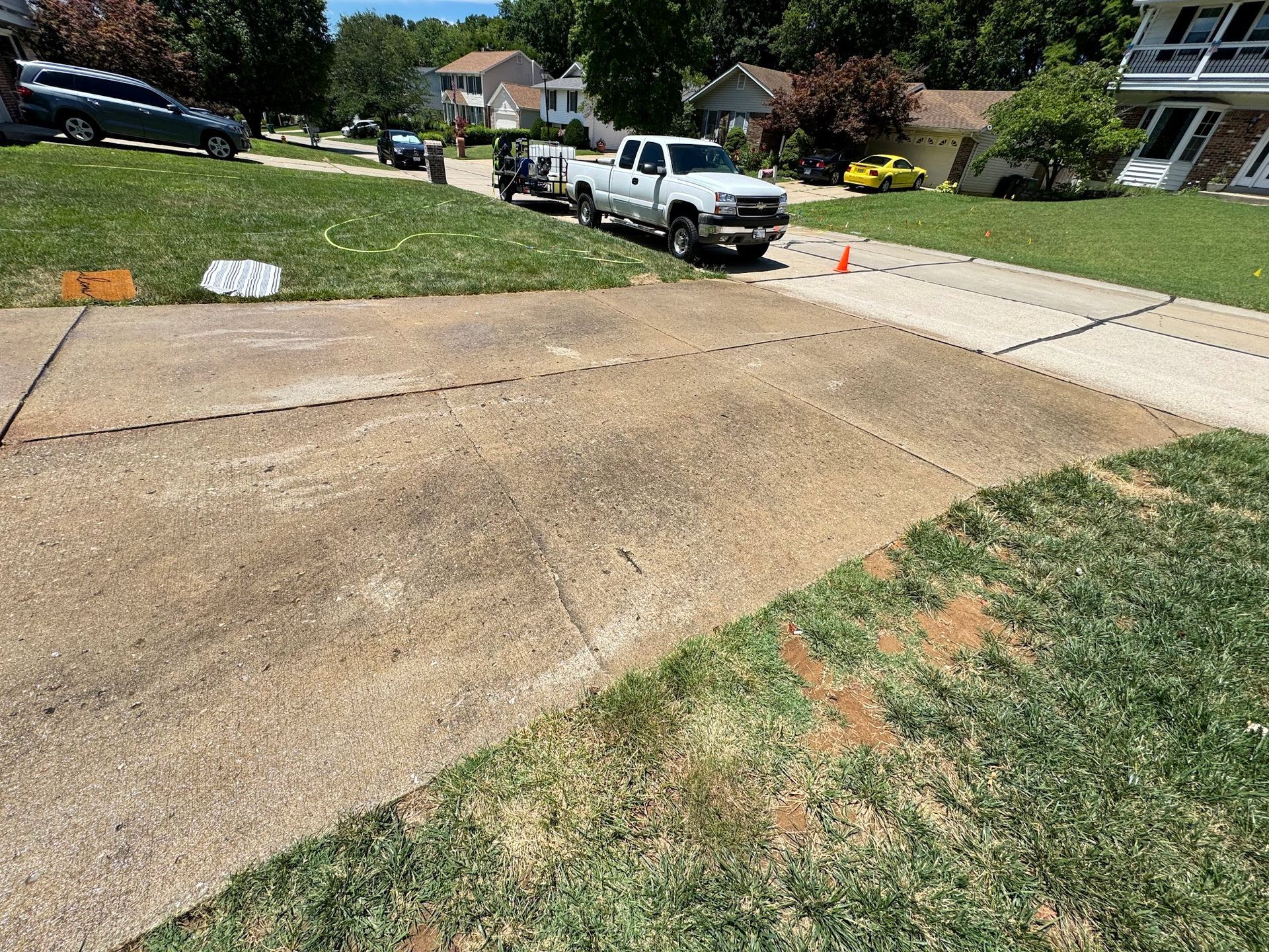 Driveway with parked white truck and other vehicles on a sunny day.