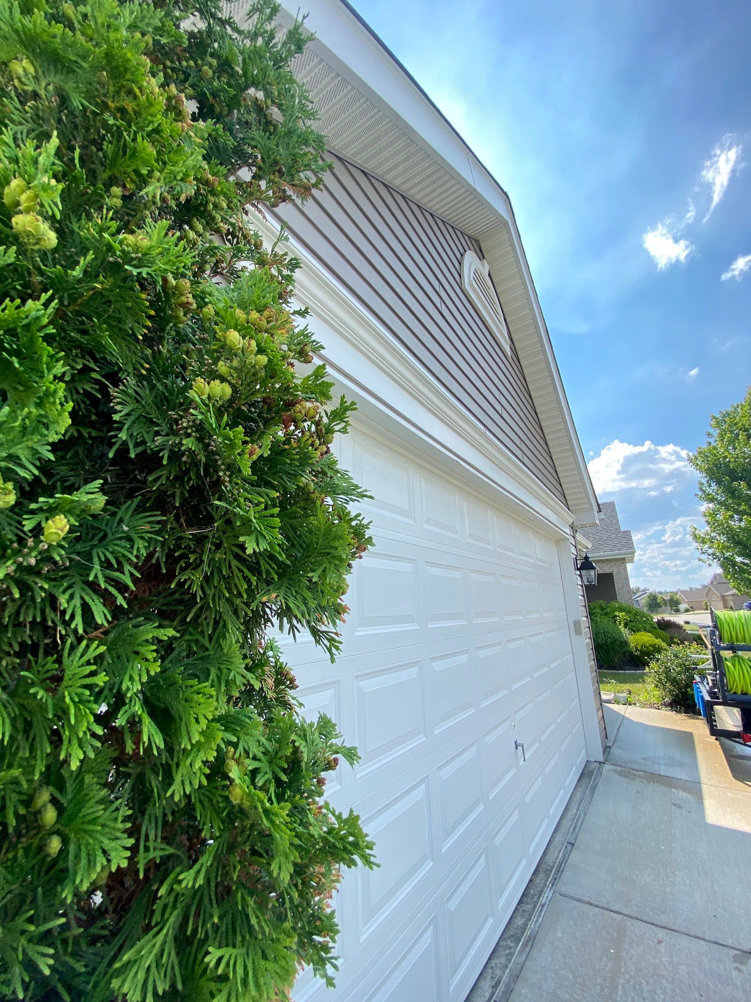 White garage with a small tree to the left, beneath a blue sky.
