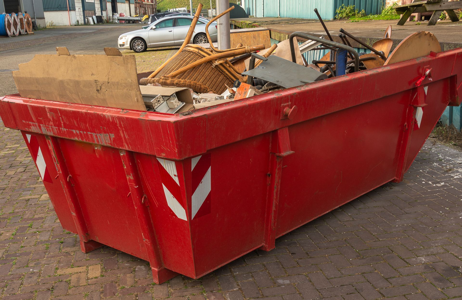 Red dumpster filled with discarded items outdoors.