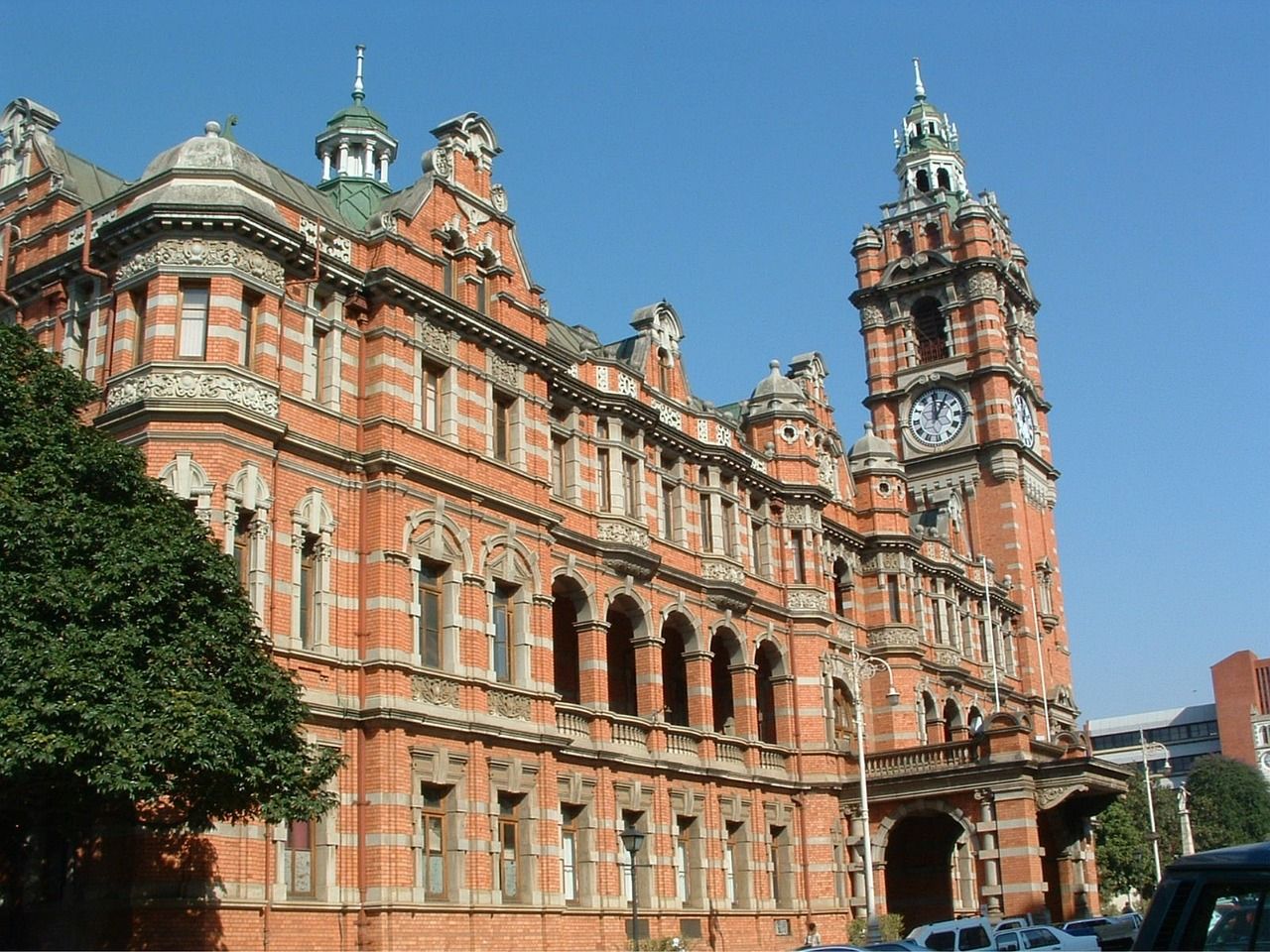 Brick building with clock tower and ornate details against a blue sky.